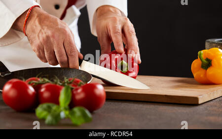 https://l450v.alamy.com/450v/rcdr54/male-chef-cutting-fresh-capsicum-or-sweet-peppers-on-a-wooden-board-using-a-large-sharp-knife-rcdr54.jpg