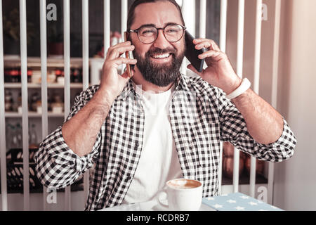 Busy man using two smartphones simultaneously while talking Stock Photo