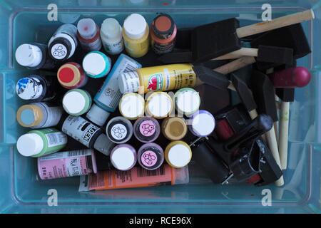 A plastic container full of acrylic paints, foam brushes, and rollers, as seen from above. Stock Photo