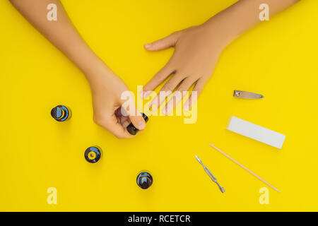 Woman Hands Care. Top View Of Beautiful Smooth Woman's Hands With Professional Nail Care Tools For Manicure On yellow Background. Closeup Of Healthy Female Nails With yellow Nail Polish. High Resolution Stock Photo