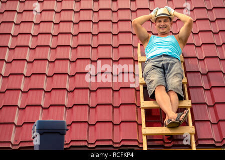 Happy man posing on the stairs against the background of the roof of the house, making repairs cover Stock Photo