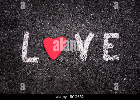 Valentines day card, word Love written on asphalt background with a red stone in the shape of a heart Stock Photo