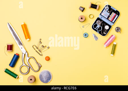 Composition with threads and sewing accessories - scissors, centimeter, pins on yellow background. Stock Photo