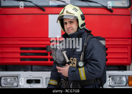 Photo of man fireman with mask in hands near fire truck