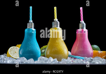 Trio of fun chilled cocktails in colored glass bulbs blended with fresh fruit ingredients including lemon, lime, orange and kiwi and served on crushed Stock Photo