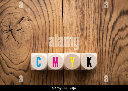 cubes with colored letters for CMYK on wooden background Stock Photo