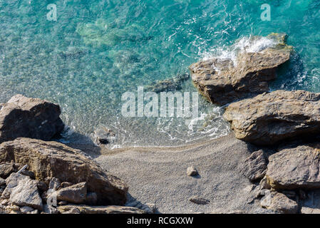 Aerial view of sea waves crashing on a fantastic beach and rocky coast. Blue sea and coastline seen from above with footprints on the sand. Stock Photo