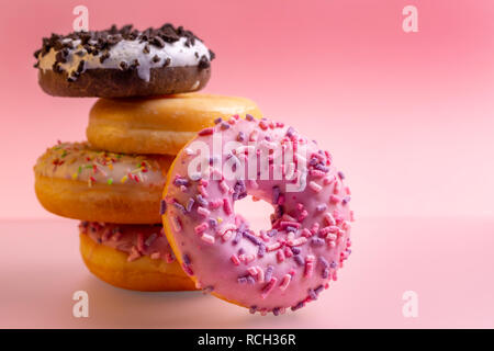 Stack of colorful donuts on pink background. Stock Photo