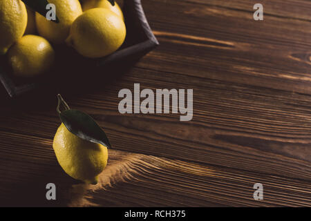 Fresh yellow lemons with leaves on wooden table. Stock Photo