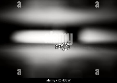 Black and white photo of a pair of rings on a mirror surface. Close-up shot Stock Photo