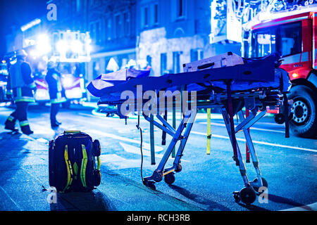 Eine Trage für Verletzte und ein Rucksack von Rettungskräften steht während eines Brandes vor einem Mehrfamilienhaus. Stock Photo
