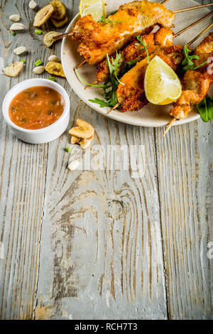 West african food, spicy nigerian chicken kebabs with peppered sauce, chin chin and dry plantains, wooden background copy space top view Stock Photo