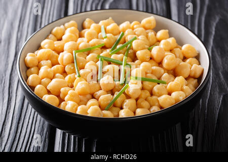 Cooked chickpeas close-up in a black bowl on a wooden table. horizontal background Stock Photo