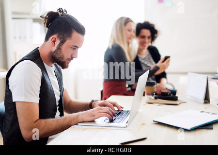 Group of young businesspeople with laptop working in a modern office. Stock Photo
