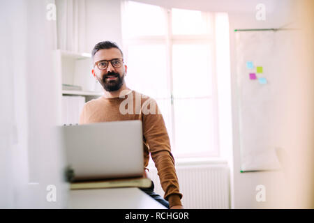 Mature hipster businessman with laptop working in a modern office. Stock Photo