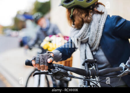 Active senior couple with electrobikes standing outdoors on a road in town. Stock Photo