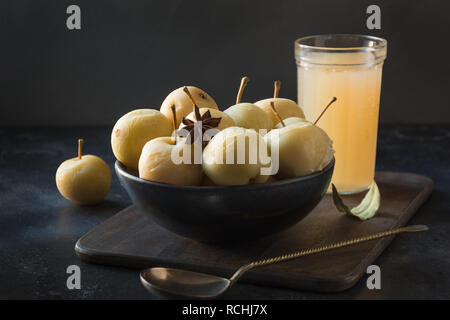Pickled apples in bowl and apple sidr in glass on dark stone table. Traditional Russian food. Stock Photo