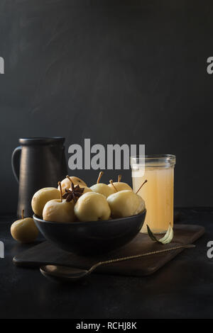 Pickled apples in bowl and apple sidr in glass on dark stone table. Traditional Russian food. Stock Photo