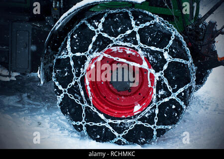 Winter scenery. Logging machine giant wheels equipped with snow chains. Tractor wheels in chains for winter Stock Photo