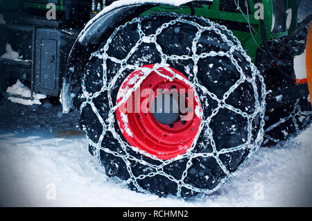 Winter scenery. Logging machine giant wheels equipped with snow chains. Tractor wheels in chains for winter Stock Photo