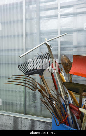 Garden tools stored outside at an allotment ready for use. Stock Photo