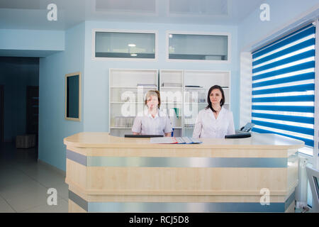 Two smiling nurses working at hospital reception desk Stock Photo