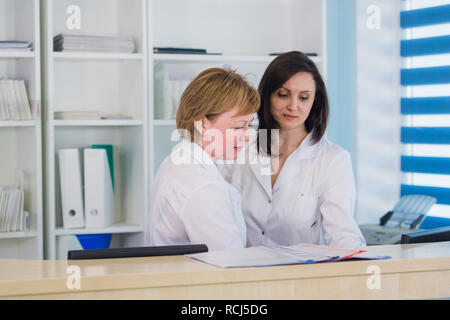 Two smiling nurses working at hospital reception desk Stock Photo