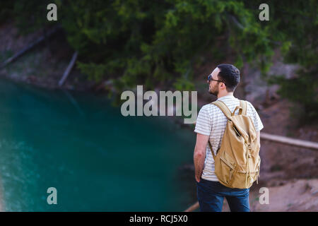 man on the background of nature with a backpack on his back. Man looks into the distance Stock Photo