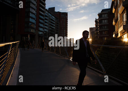 Pedestrians making their way home in the evening over the River Irwell from offices in Spinningfields, Manchester. Stock Photo