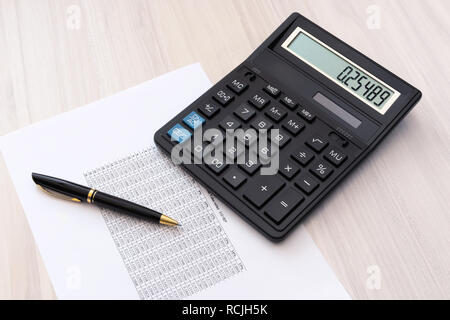 Calculator, pen and sheet of paper with spreadsheet  on the table Stock Photo