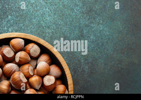 Hazelnuts in wooden bowl on textured background Stock Photo