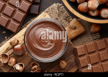 Chocolate spread, nuts and chocolate bars on table Stock Photo