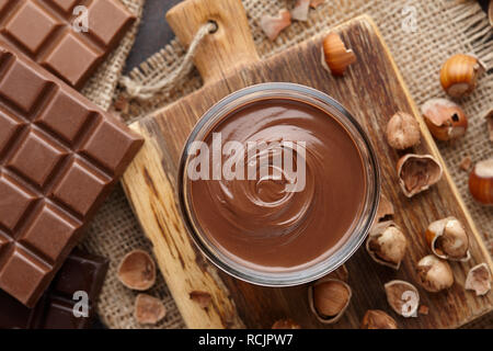 Chocolate spread, nuts and chocolate bars on table Stock Photo