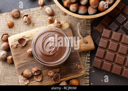 Chocolate spread, nuts and chocolate bars on table Stock Photo
