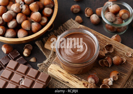 Chocolate spread, nuts and chocolate bars on table Stock Photo