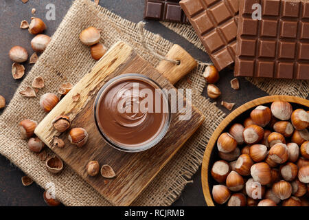 Chocolate spread, nuts and chocolate bars on table Stock Photo