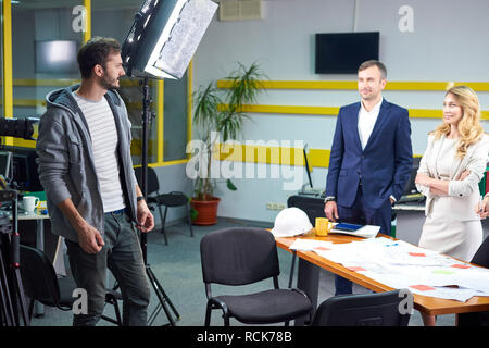 Film director discussing movie plan with the actors in the office scene. Lights pointing to the actors Stock Photo