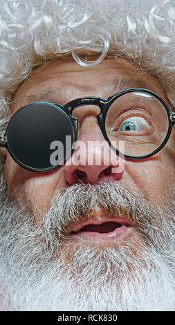 Santa Claus with surprised expression. Christmas celebration concept. The emotional face of Santa Clause in glasses. The holiday, expression, emotions, senior, winter, gesture concept. The facial expression concept Stock Photo