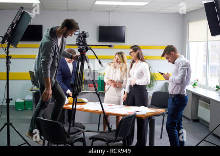 Film director discussing movie plan with the actors in the office scene. Lights pointing to the actors Stock Photo