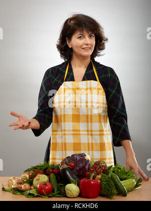 Housewife in apron with a bunch of vegetables on the table Stock Photo