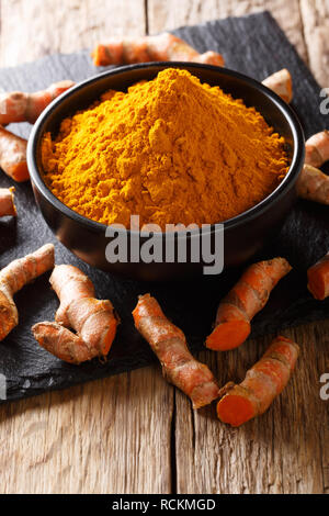 Fresh turmeric spice in a bowl and root close-up on the table. vertical Stock Photo