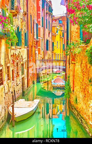 Venetian canal with small bridge and moored boats on sunny summer day, Venice, Italy Stock Photo