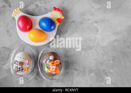 Multi-colored Easter eggs lie on a white plate in the shape of a chicken next to paint for coloring and Easter cakes. Copy space. Stock Photo