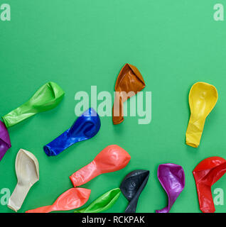 colorful deflated balloons on a green background, copy space Stock Photo