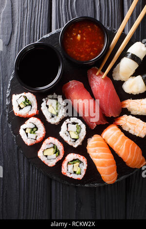 set of Japanese rolls of uramak and nigiri served with two sauces close-up on a slate plate. Vertical top view from above Stock Photo