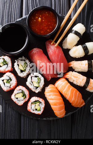 Set of fresh maki, uramaki and nigiri sushi, served on black plate close-up. Vertical top view from above Stock Photo
