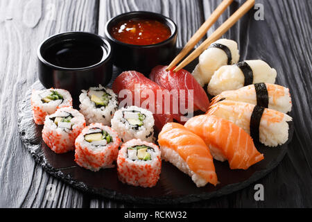 Uramaki and nigiri sushi served in black plate closeup on wooden table. horizontal Stock Photo