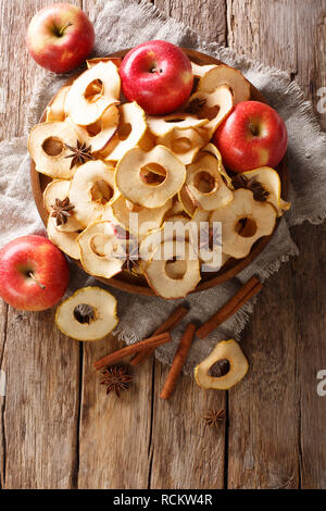 Apple chips with cinnamon and star anise close-up on a plate on the table. Vertical top view from above Stock Photo
