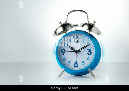 Blue and white analogue retro alarm clock ringing, plain background, white background Stock Photo