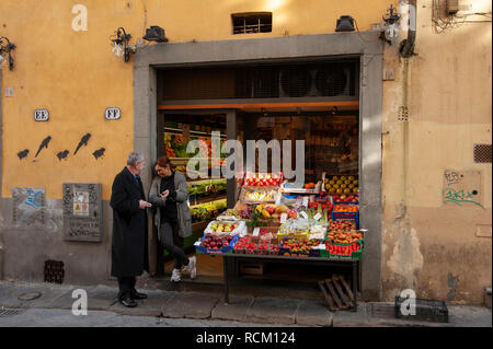A customer and store owner in discussion in the doorway to a local greengrocer shop, Florence, Italy Stock Photo